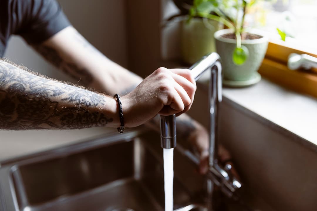 narbild-pa-hander-som-kontrollerar-en-nyinstallerad-blandare-i-ett-kok